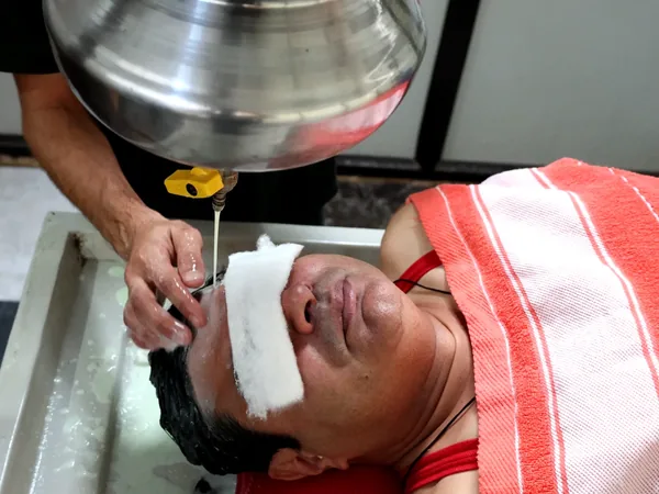 Shirodhara warm medicated oil therapy on the forehead